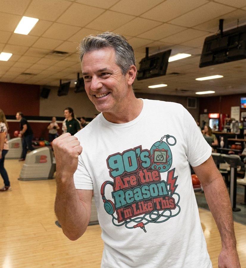 Man in a white tee reading "90's Are the Reason I'm Like This" with a virtual pet and headphones graphic, smiling at a bowling alley
